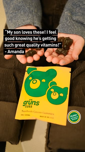 An image featuring a person\'s hands holding dark green gummy bear vitamins and a yellow packet. The packet has a green bear design and text related to the product. A quote overlay shows a customer testimonial about the product. The background shows the person\'s sweater and clothing.