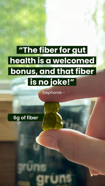A hand holds a gummy bear-shaped supplement against a soft background of a blurred outdoor setting, possibly a window. The image displays a close-up of the supplement being pinched between the index finger and thumb. A quote in a green rectangle is displayed, "The fiber for gut health is a welcomed bonus, and that fiber is no joke!". The text "Stephanie" is displayed under the quote. A small green rectangle, bottom left of frame states, "6g of fiber". Behind the gummy, a green jar is partially visible