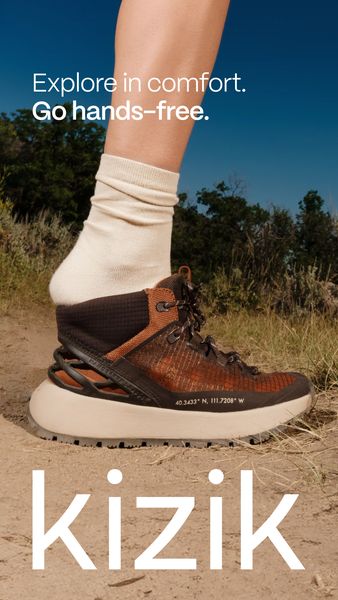 The ad features a person's lower leg and foot wearing a hiking boot walking on a dirt path. In the background, lush green foliage and a blue sky are visible. The shoe, a modern hiking boot, is the focal point of the image. The ad's layout is vertical, with branding and tagline elements.