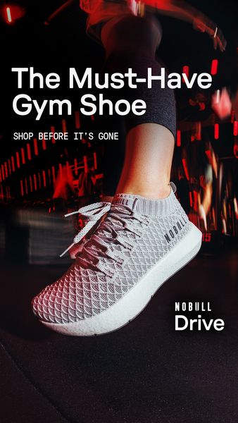 An image showcasing a gray and white athletic shoe on a person's foot. The shoe is a sneaker with a knitted upper and white sole and laces. The person is wearing dark-colored workout attire, and the shoe fills a lot of the frame. The background is blurred, but appears to be an exercise space. The lighting is dynamic, suggestive of activity and movement.