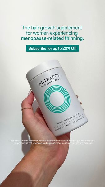 The ad features a woman's hand holding a white cylindrical bottle with a teal label. The bottle is angled slightly and takes up most of the frame. The label reads 'NUTRAFOL WOMEN'S BALANCE'. Above the bottle are the words 'The hair growth supplement for women experiencing menopause-related thinning.' Below the bottle, there is a disclaimer. In the background, the ad is set against a plain white backdrop.