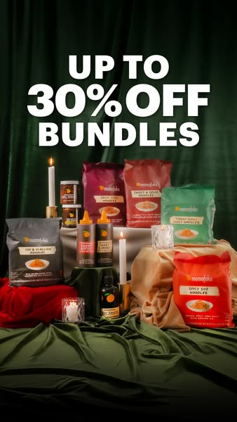 An inviting product advertisement featuring various food packages. The composition is a festive display with a dark green velvet backdrop that resembles a curtain, creating a luxurious background. In the foreground, a combination of rich red and tan silky fabrics is elegantly draped, serving as the stage for the food items. The items displayed include several bags and jars of noodles and sauces. The product arrangement is enhanced by lit candles placed at different levels, providing warm illumination and depth. The text at the top of the image states 'UP TO 30% OFF BUNDLES' in bold white letters.