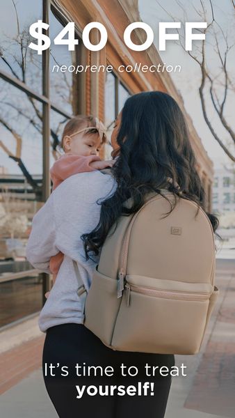 The image shows a woman holding a baby, with a cream-colored backpack slung over her shoulder. The woman is wearing a gray hoodie and black leggings, and the baby is wearing a pink outfit. The background features a modern building. Text overlayed on the image reads '$40 OFF' and 'It's time to treat yourself!' to promote the sale.