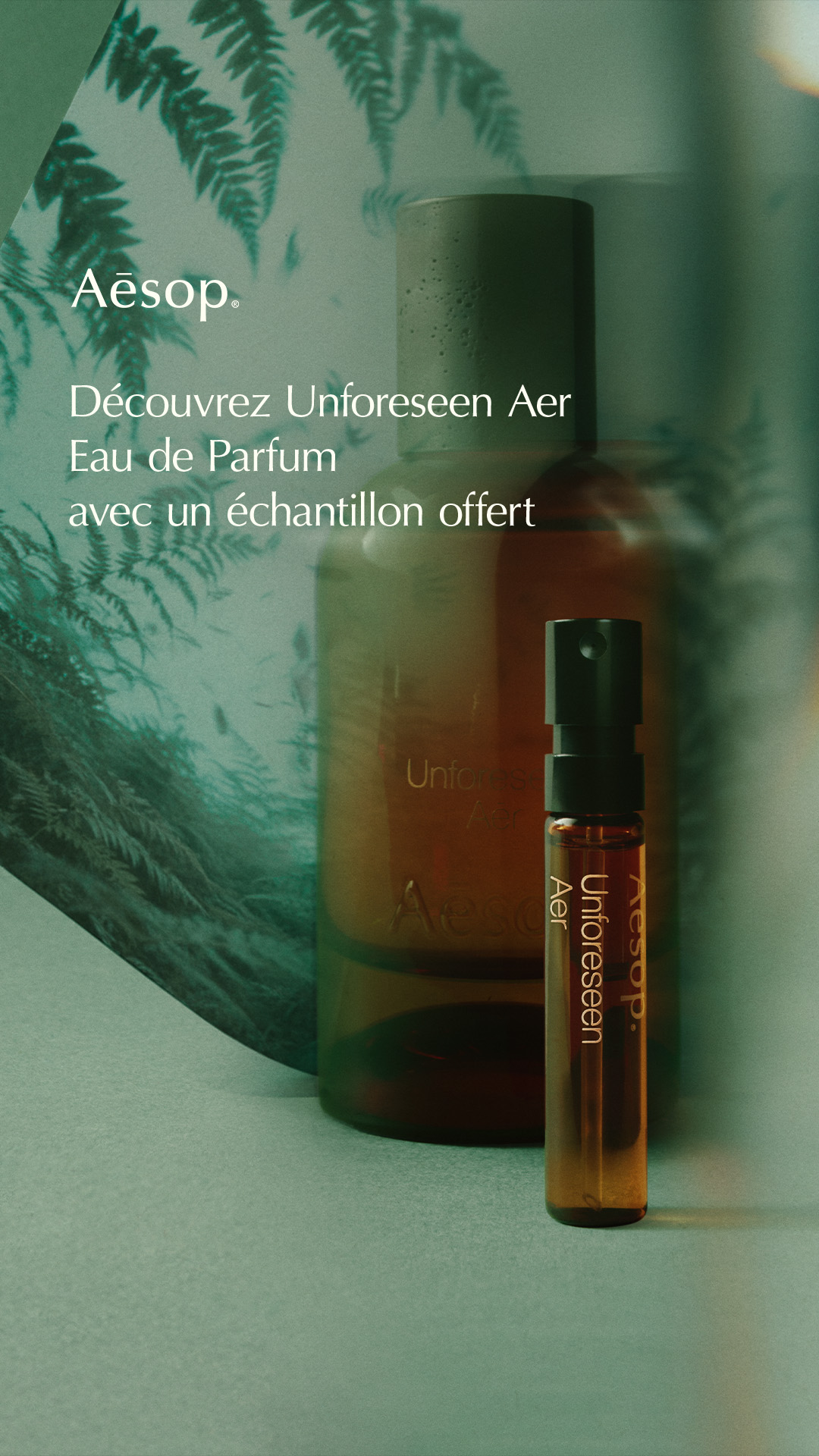 The creative features a close-up shot of Aesop perfume bottles against a backdrop of green foliage. The main focus is on a small sample vial and a larger bottle of "Unforeseen Aer" Eau de Parfum. White text overlays the image, announcing the discovery of the new fragrance and a complimentary 2ml sample with every order. The overall aesthetic is sophisticated and natural, highlighting the product and the offer.