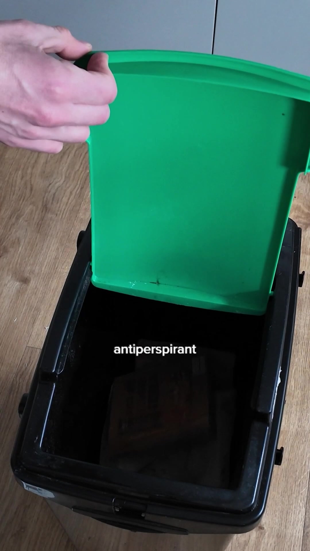 A person's hand is shown opening the bright green lid of a black container. The word "antiperspirant" is displayed in white text across the inside of the container. The container appears to be a refillable deodorant dispenser. The overall visual suggests a product demonstration with text overlay highlighting the product category.