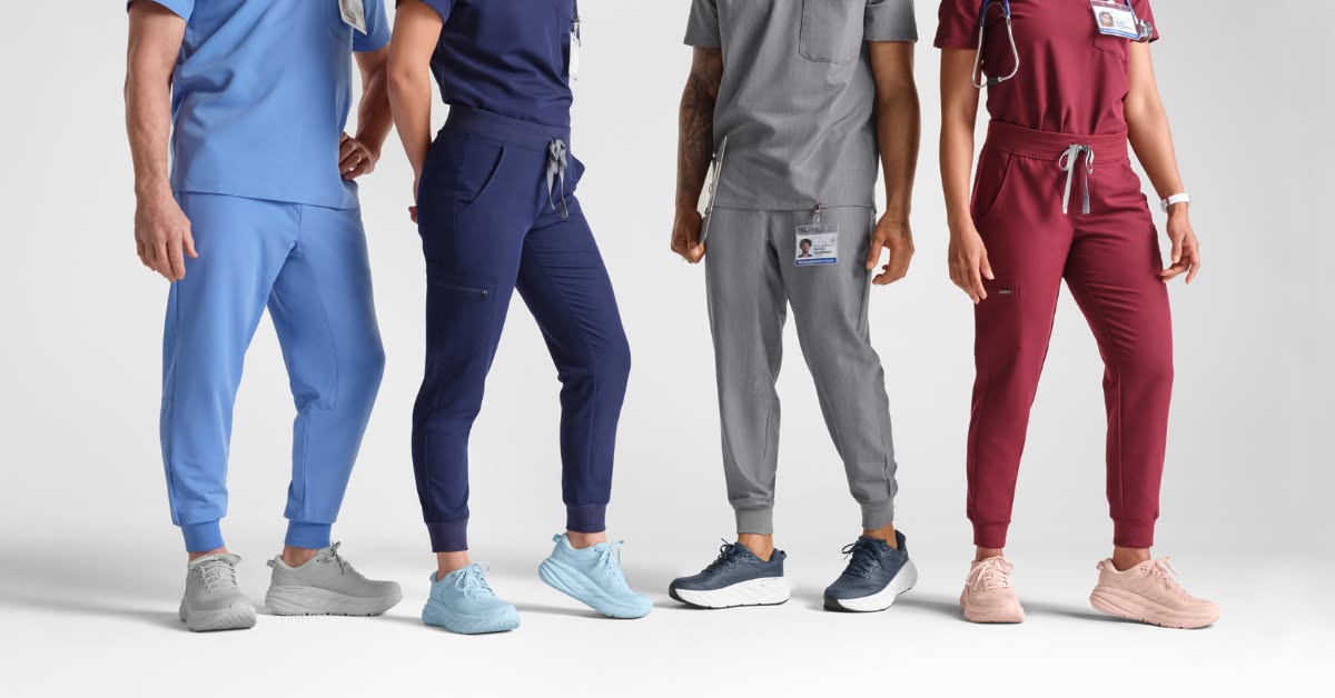 Four individuals, two men and two women, are shown from the waist down, all wearing different colored Hoka shoes and matching scrubs. The first person on the left wears light blue scrubs and grey shoes. The second person wears dark blue scrubs and light blue shoes. The third person wears grey scrubs and dark blue shoes. The fourth person wears burgundy scrubs and pink shoes. The text overlay announces a 15% discount for verified medical providers on full-priced footwear at HOKA.com.