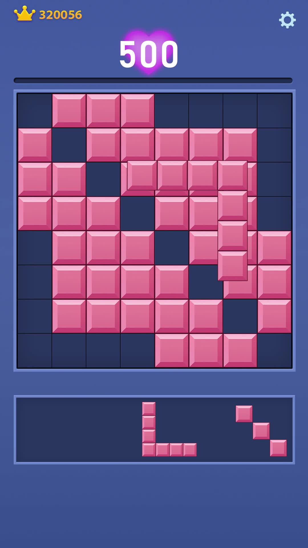 The creative shows a screenshot of a mobile puzzle game called Block Blast. The game board is partially filled with pink blocks and dark blue empty spaces. Below the board, there are two sets of puzzle pieces that can be placed on the board. The score is displayed as 500, and there is a crown icon with the number 320056 next to it. The hook is a question asking, "Can you clear the board?"