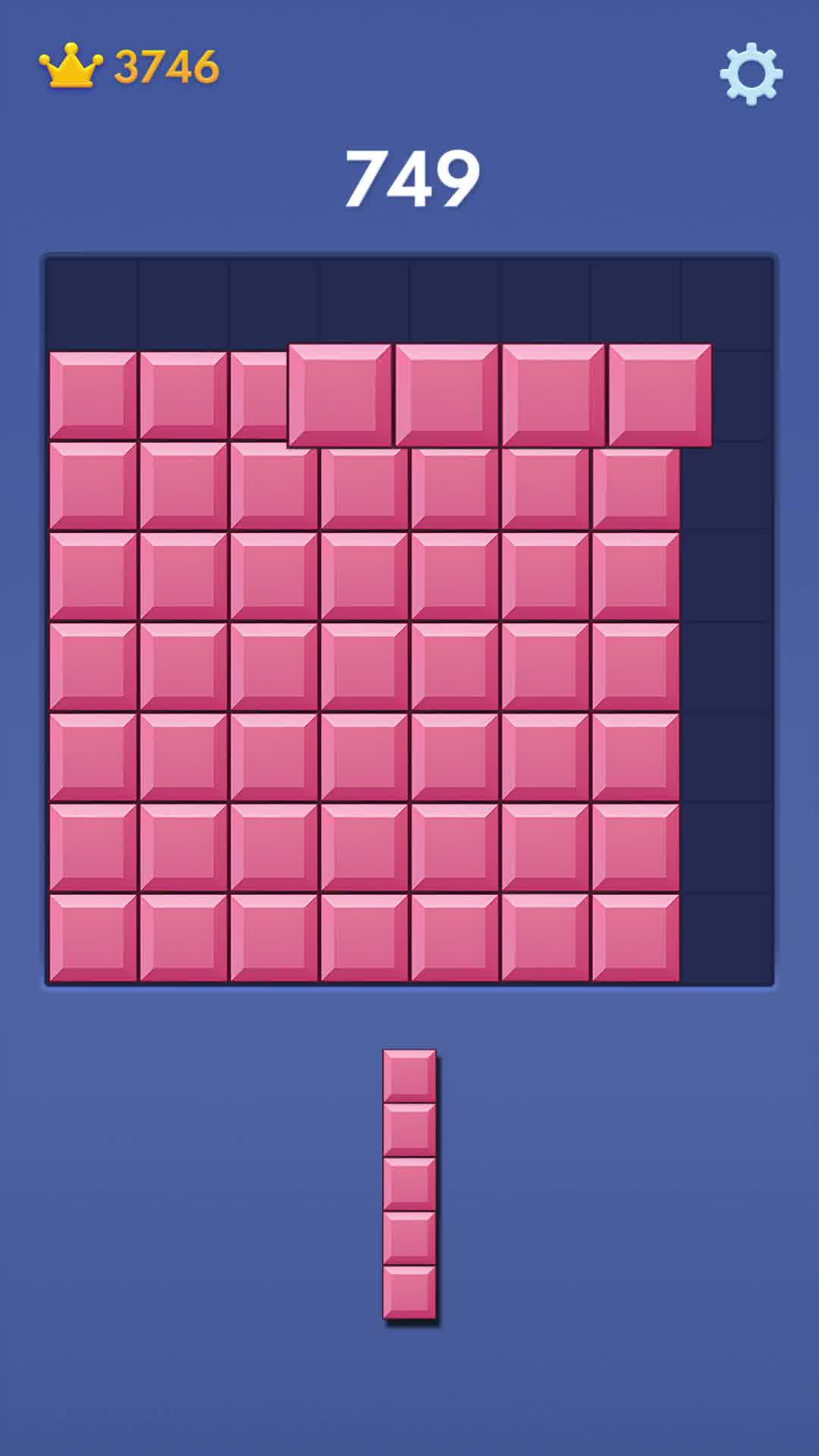The creative displays a screenshot of the mobile game Block Blast. The screen shows a game board filled with pink blocks, with a score of 749 at the top. Below the board, a single vertical block piece is shown, ready to be placed. The game interface also shows a crown icon with the number 3746, likely representing points or currency. The overall visual is clean and focuses on the gameplay interface.