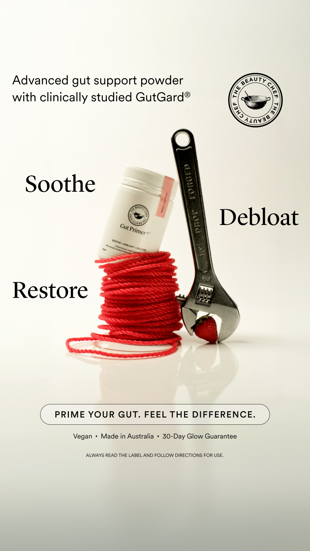 A white bottle of "Gut Primer+" powder is shown, wrapped in red string. To the right, a wrench is gripping a strawberry, with the word "Debloat" to its right. To the left of the bottle, the word "Soothe" is displayed, and below it, the word "Restore". Above the bottle, text reads "Advanced gut support powder with clinically studied GutGard®". A circular logo for "The Beauty Chef" is in the upper right corner. At the bottom, a banner reads "PRIME YOUR GUT. FEEL THE DIFFERENCE." followed by "Vegan • Made in Australia • 30-Day Glow Guarantee" and "ALWAYS READ THE LABEL AND FOLLOW DIRECTIONS FOR USE."