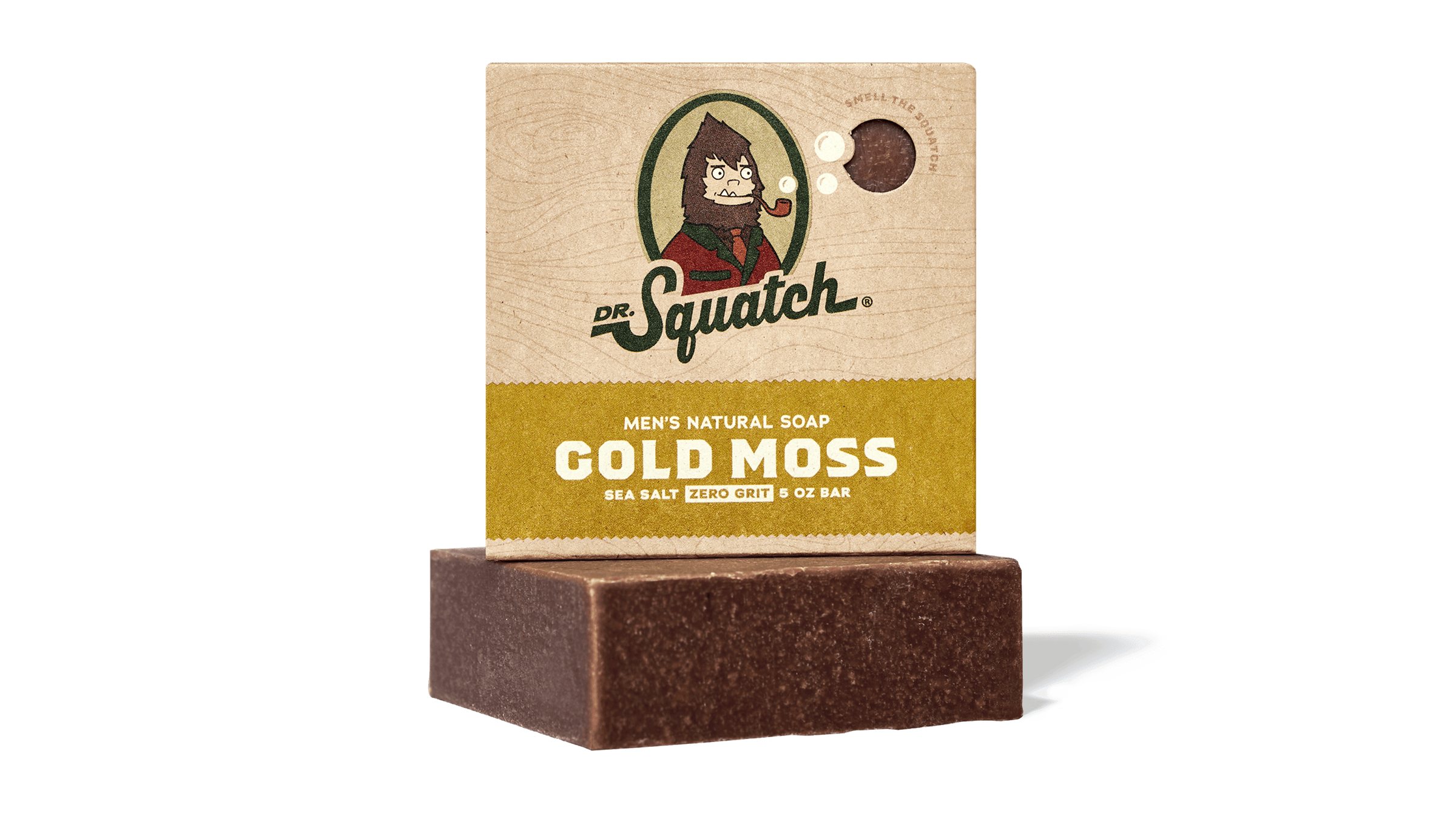 A product shot of Dr. Squatch Gold Moss soap bar, with its packaging box placed behind it. The packaging features a cartoon illustration of Bigfoot smoking a pipe and the brand logo. Text overlays on the packaging read "MEN'S NATURAL SOAP", "GOLD MOSS", and "SEA SALT ZERO GRIT 5 OZ BAR". The hook "Simply good natural soap formulated for men" is overlaid on the image.