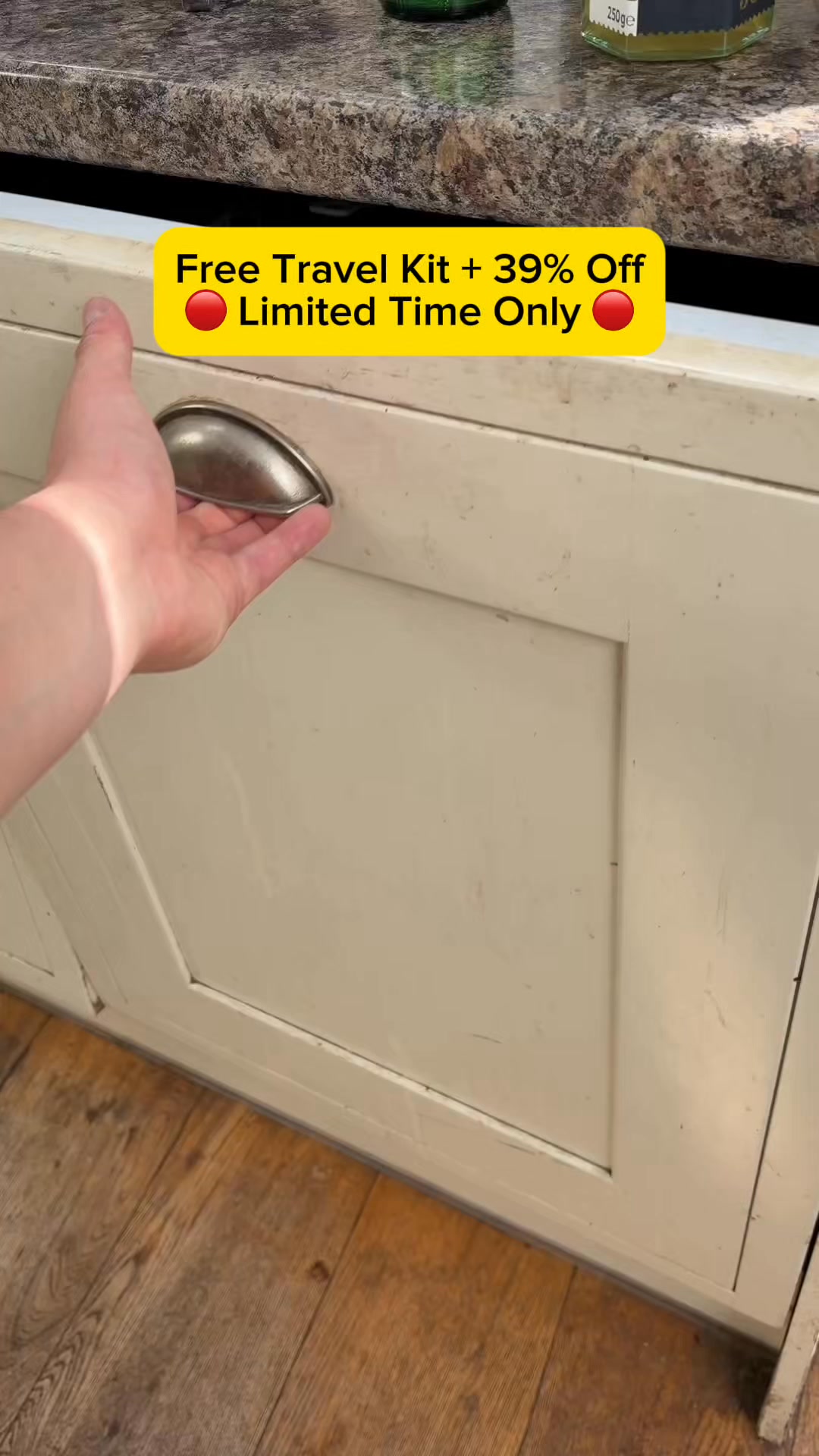 A hand is reaching for a cabinet handle. A yellow banner with red text is overlaid on the image. The text reads "Free Travel Kit + 39% Off" and "Limited Time Only" with a red circle icon next to each line. The background shows a kitchen counter and cabinets.