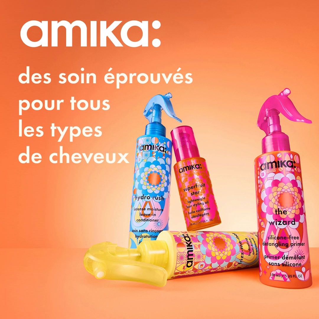 The Amika logo is displayed prominently at the top of an orange background. Below the logo, text in French reads "des soins éprouvés pour tous les types de cheveux," which translates to "proven care for all hair types." The image features three Amika hair products: a blue spray bottle labeled "hydro rush," a small pink bottle labeled "superfruit star," and a pink spray bottle labeled "the wizard." A yellow spray bottle is also visible, partially obscured. The products are arranged in a visually appealing composition against the gradient orange backdrop.