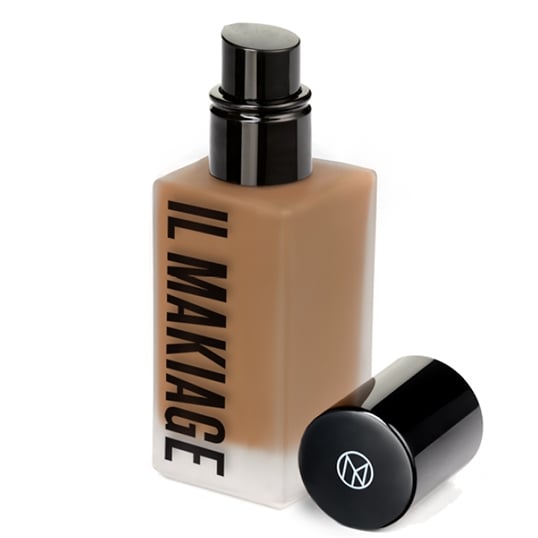 A studio shot of a bottle of IL MAKIAGE foundation against a white background. The bottle is square with a black pump dispenser and a black cap lying on its side next to it. The text "IL MAKIAGE" is printed vertically in black on the front of the bottle. The copy "Beauty products that works as hard as you do. 💥 High-performance formulas. Serious payoff. Find your new favorite." is overlaid on the image.