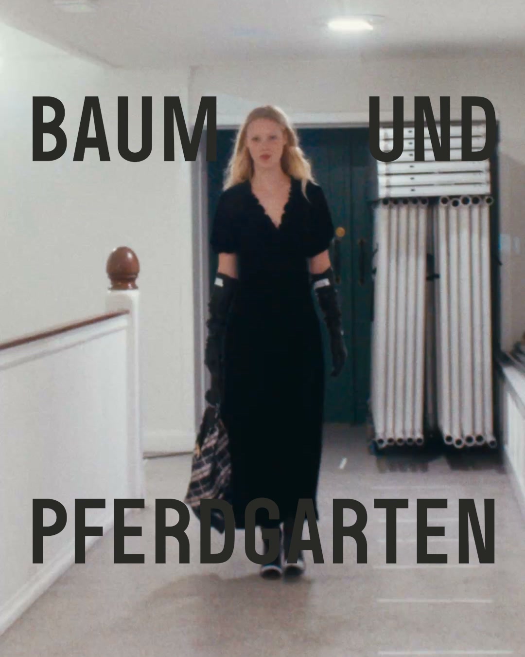 A woman in a long black dress and black gloves walks down a hallway, carrying a plaid bag. Large, bold, black text is overlaid on the image. The top line reads "BAUM UND". The bottom line reads "PFERDGARTEN". The text is positioned to frame the woman as she walks.