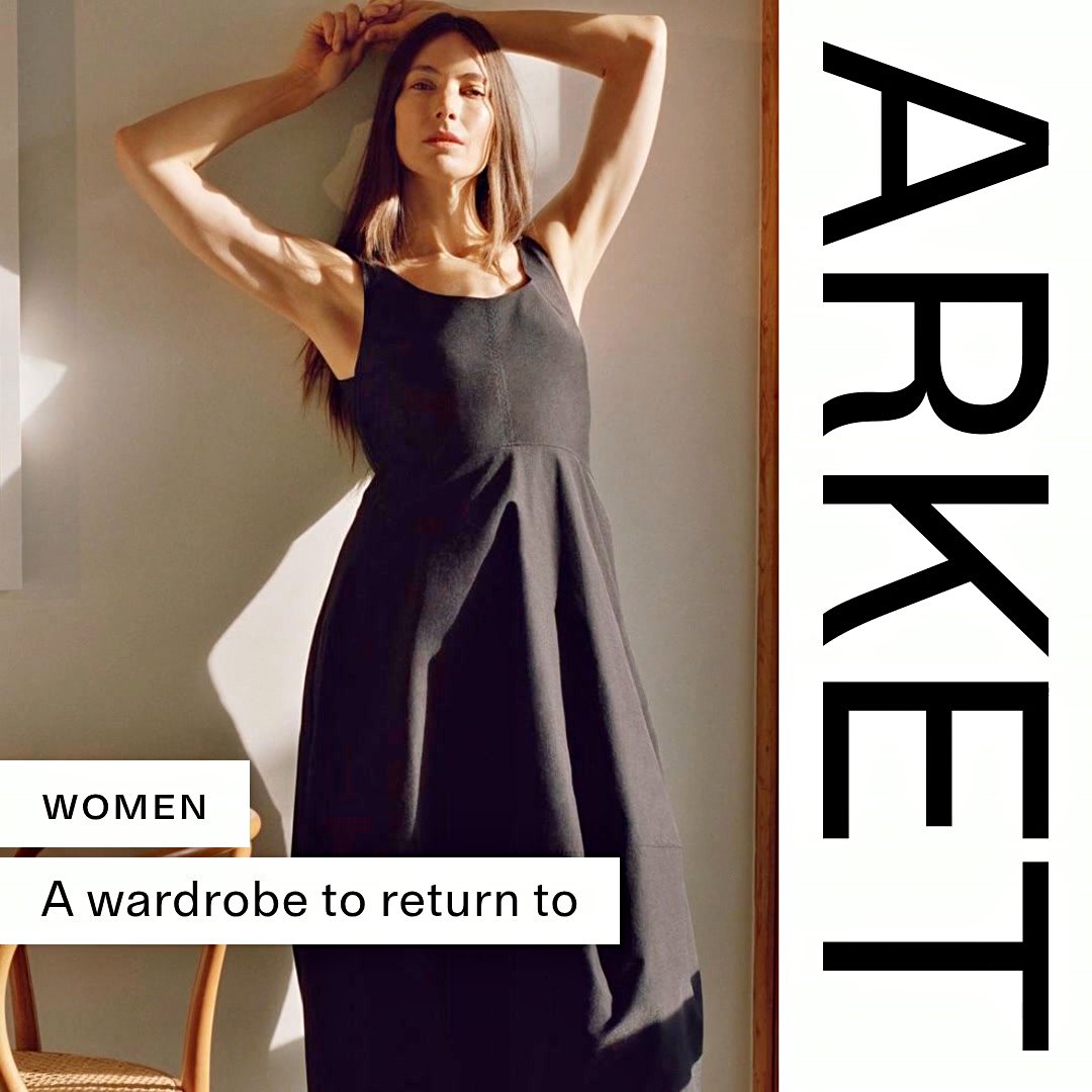 A woman leans against a wall, her arms raised above her head. She is wearing a dark, sleeveless dress. Sunlight casts shadows on the wall behind her. To the left of the image, a white box contains the word "WOMEN" and below it, another white box contains the text "A wardrobe to return to". The word "ARKET" is written vertically in large black letters on the right side of the image.