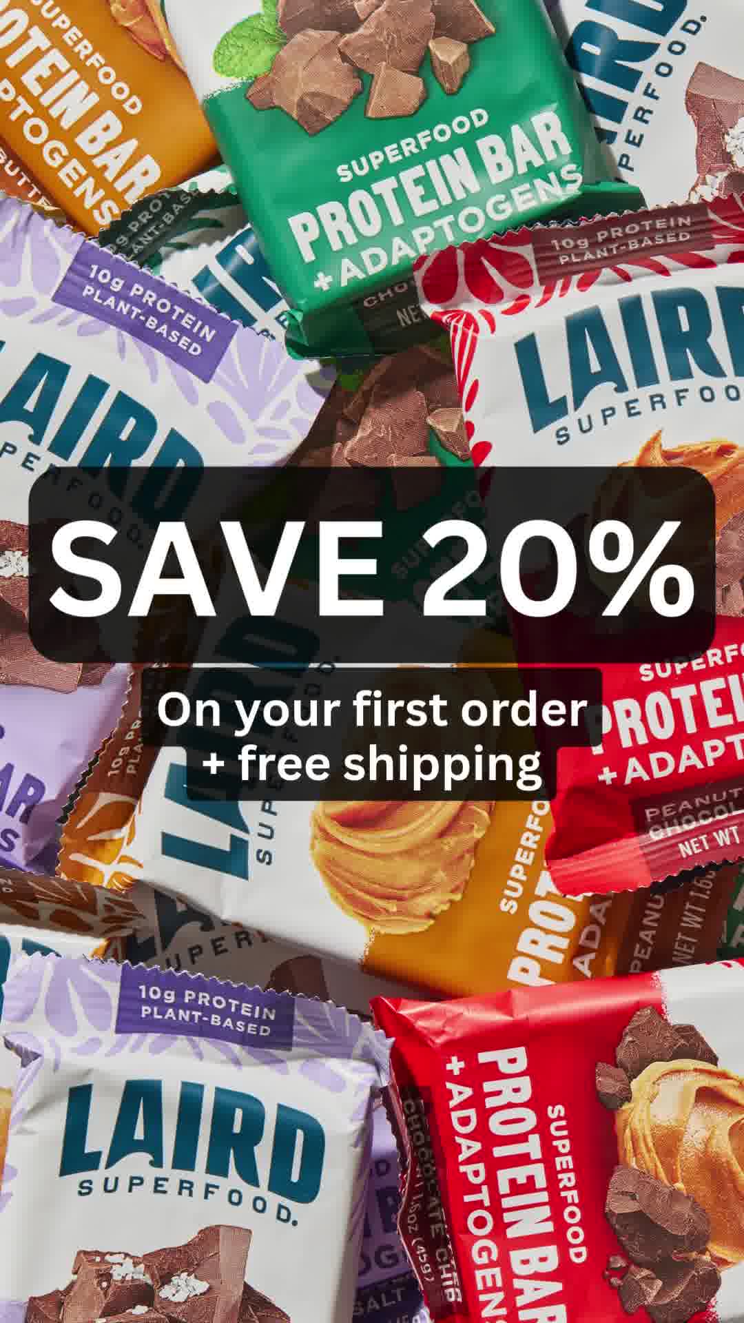 A close-up, overhead shot displays a variety of Laird Superfood Protein Bars. The bars are arranged in a scattered, overlapping pattern, with some partially visible. Prominently featured in the center of the image is a large, bold white text overlay that reads "SAVE 20%". Below this, a smaller black text overlay states "On your first order + free shipping". The overall impression is a visually rich advertisement for the protein bars, highlighting a discount offer.
