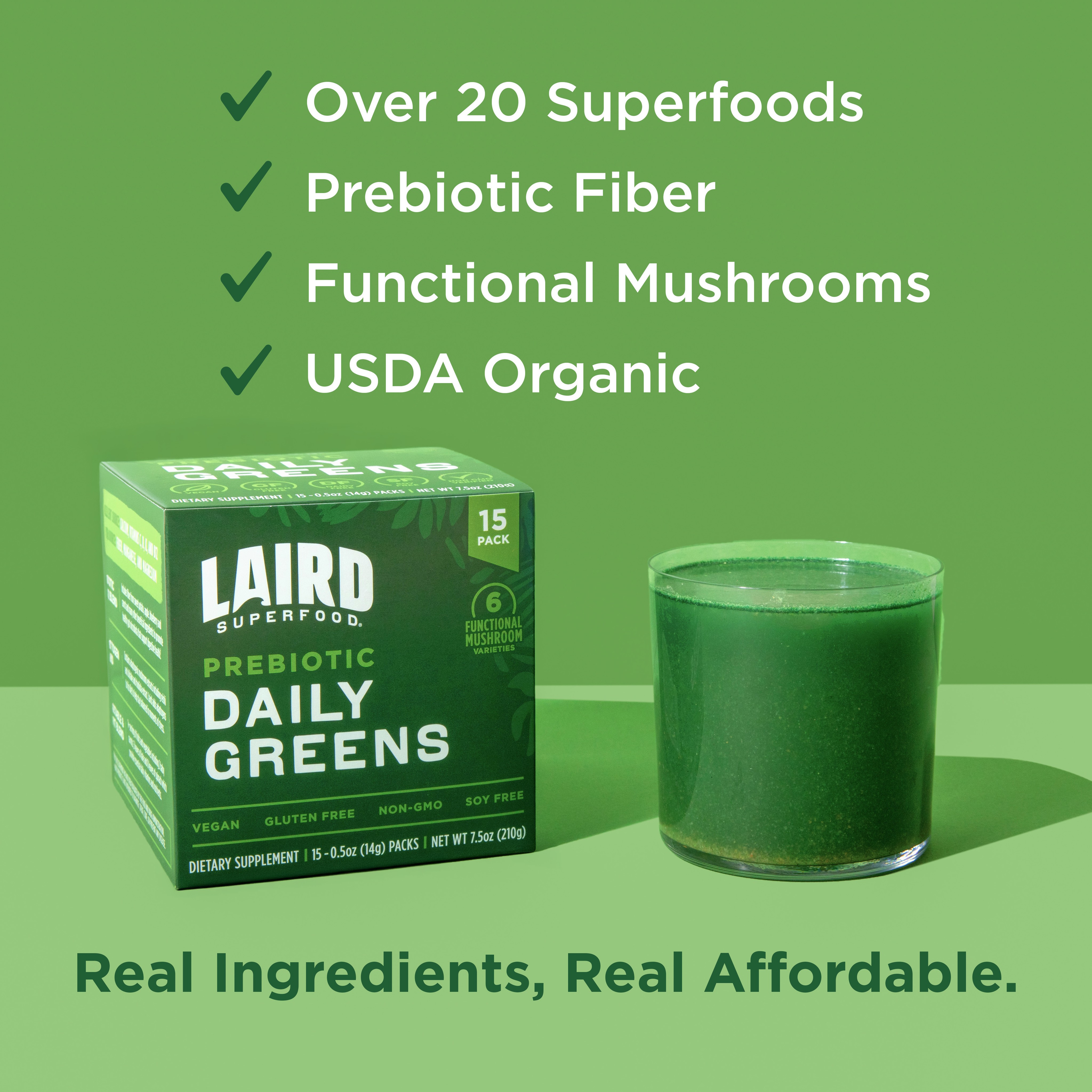 A product shot of Laird Superfood Prebiotic Daily Greens box and a glass of green liquid sits on a green background. White text overlays the image, listing benefits with checkmarks: 'Over 20 Superfoods', 'Prebiotic Fiber', 'Functional Mushrooms', and 'USDA Organic'. Below the product, large green text reads 'Real Ingredients, Real Affordable.' The creative highlights the product's features and contrasts it with a more expensive alternative.