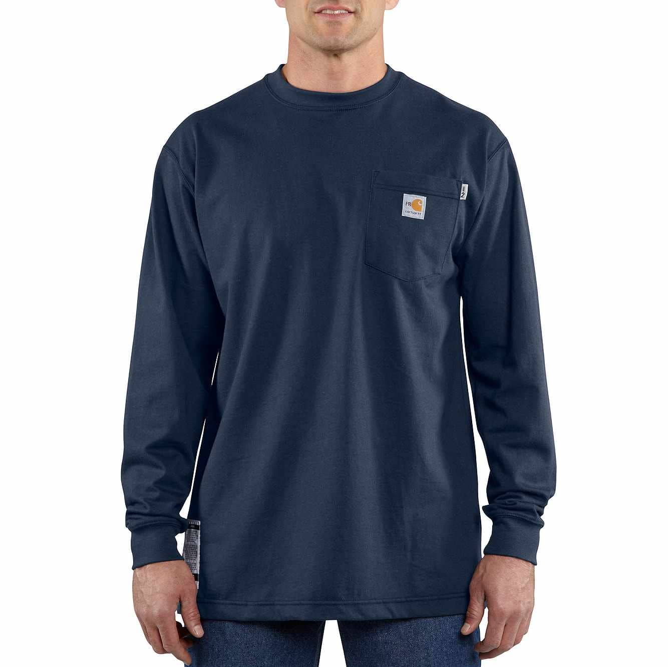 A man stands facing the camera, wearing a navy blue Carhartt long-sleeved t-shirt with a pocket on the left chest. The t-shirt has a small orange and white Carhartt logo patch on the pocket. The man is wearing blue jeans. The background is white. The text "Shop Carhartt gear that works as hard as you do." is overlaid on the image in white text with a black outline.