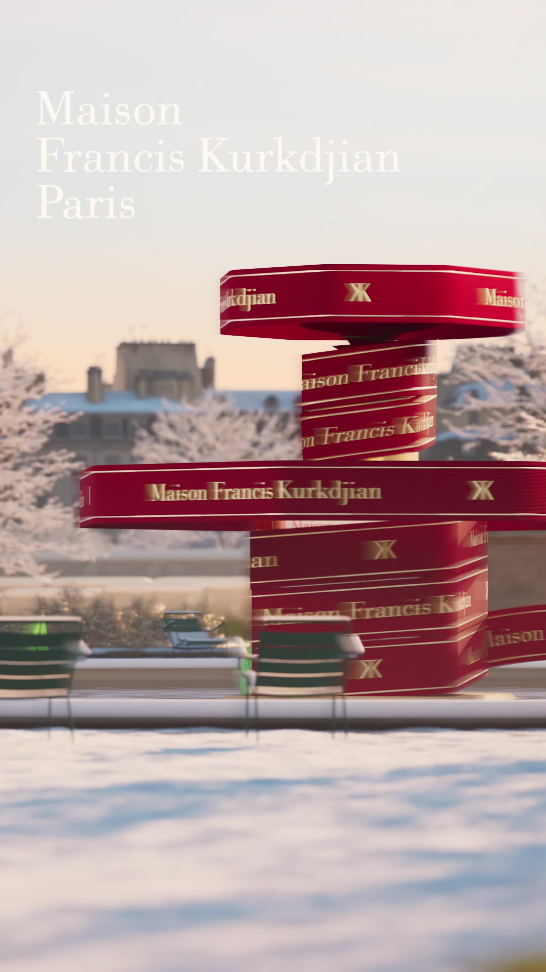 The creative features a winter scene with snow-covered trees and buildings in the background. Red ribbons with gold lettering that says "Maison Francis Kurkdjian" are wrapped around a structure in the foreground, creating a festive and luxurious visual. The text "Maison Francis Kurkdjian Paris" is overlaid in a light, elegant font at the top left of the image, setting a sophisticated and aspirational tone for the holiday season.