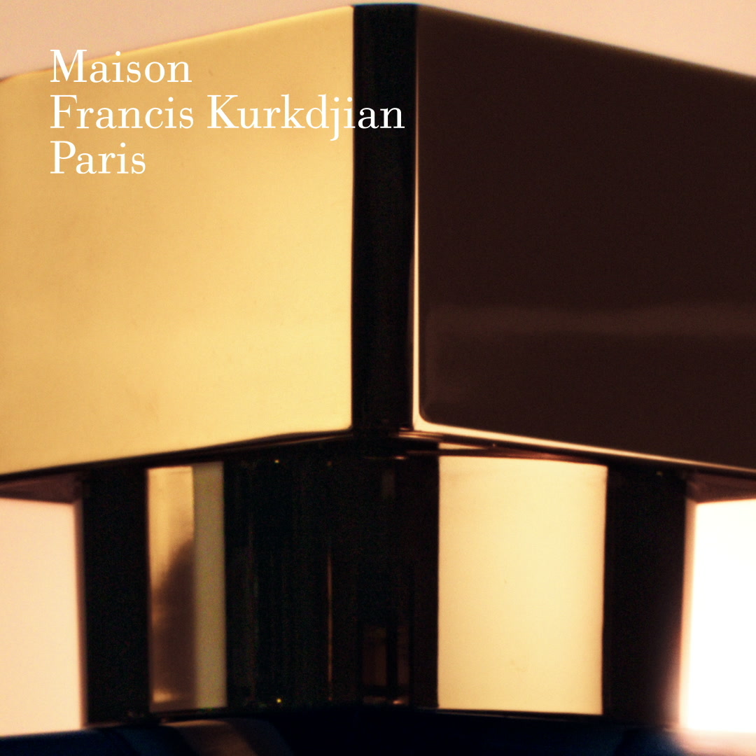 The creative is a close-up, product-focused image of the cap of a Maison Francis Kurkdjian perfume bottle. The cap is a luxurious, metallic gold with sharp, geometric edges, reflecting light. The brand name "Maison Francis Kurkdjian Paris" is overlaid in white, elegant text on the left side of the image. The overall aesthetic is sophisticated and high-end, highlighting the product's design.