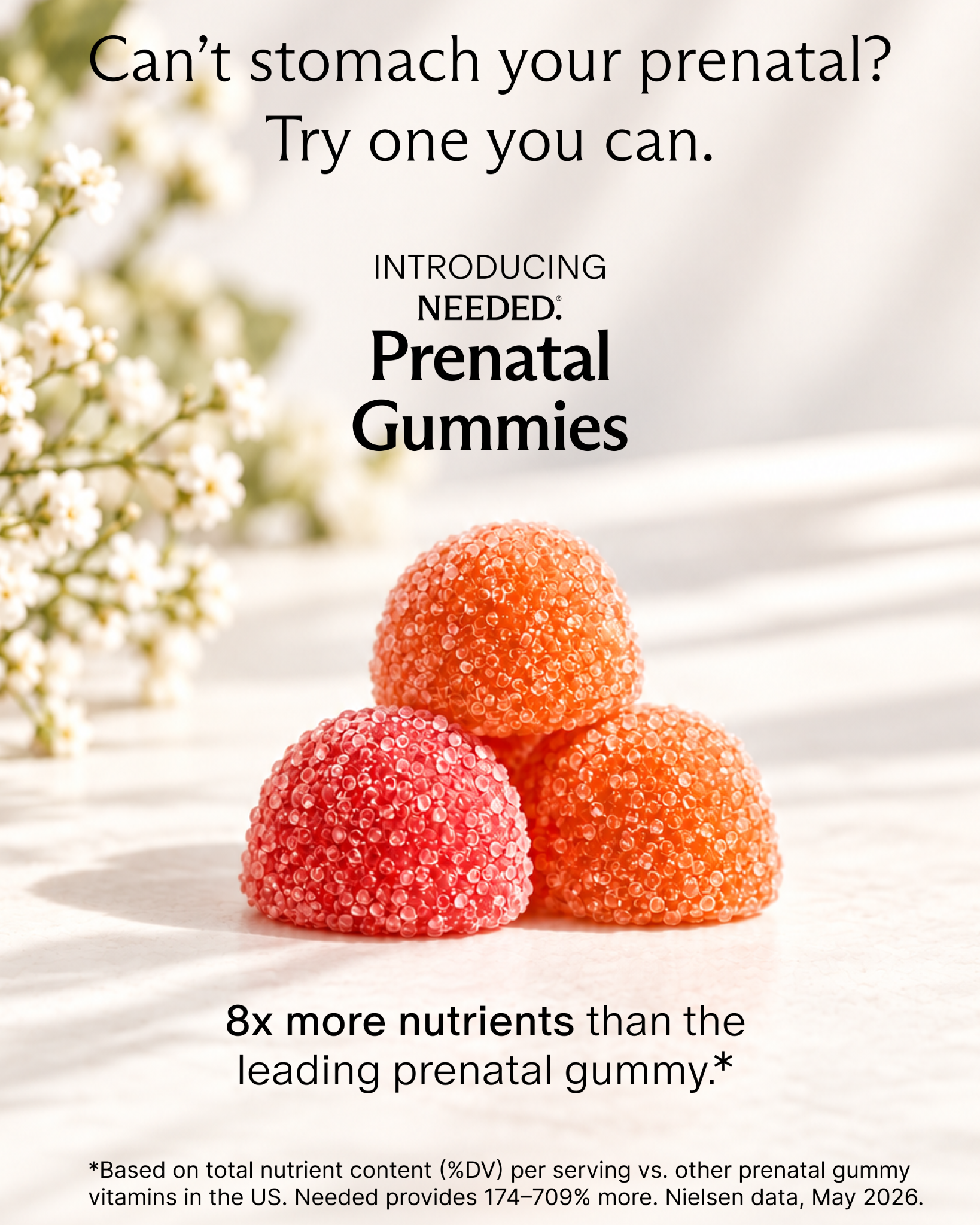 A close-up, slightly angled shot shows three gummy vitamins in shades of pink and orange, arranged in a small pile on a light-colored surface. Delicate white flowers with small blossoms are visible in the blurred background on the left. Bold black text at the top reads "Can't stomach your prenatal? Try one you can." Below the gummies, smaller text introduces "INTRODUCING NEEDED: Prenatal Gummies." At the bottom, larger text states "8x more nutrients than the leading prenatal gummy.*" A footnote with legal text is present at the very bottom.