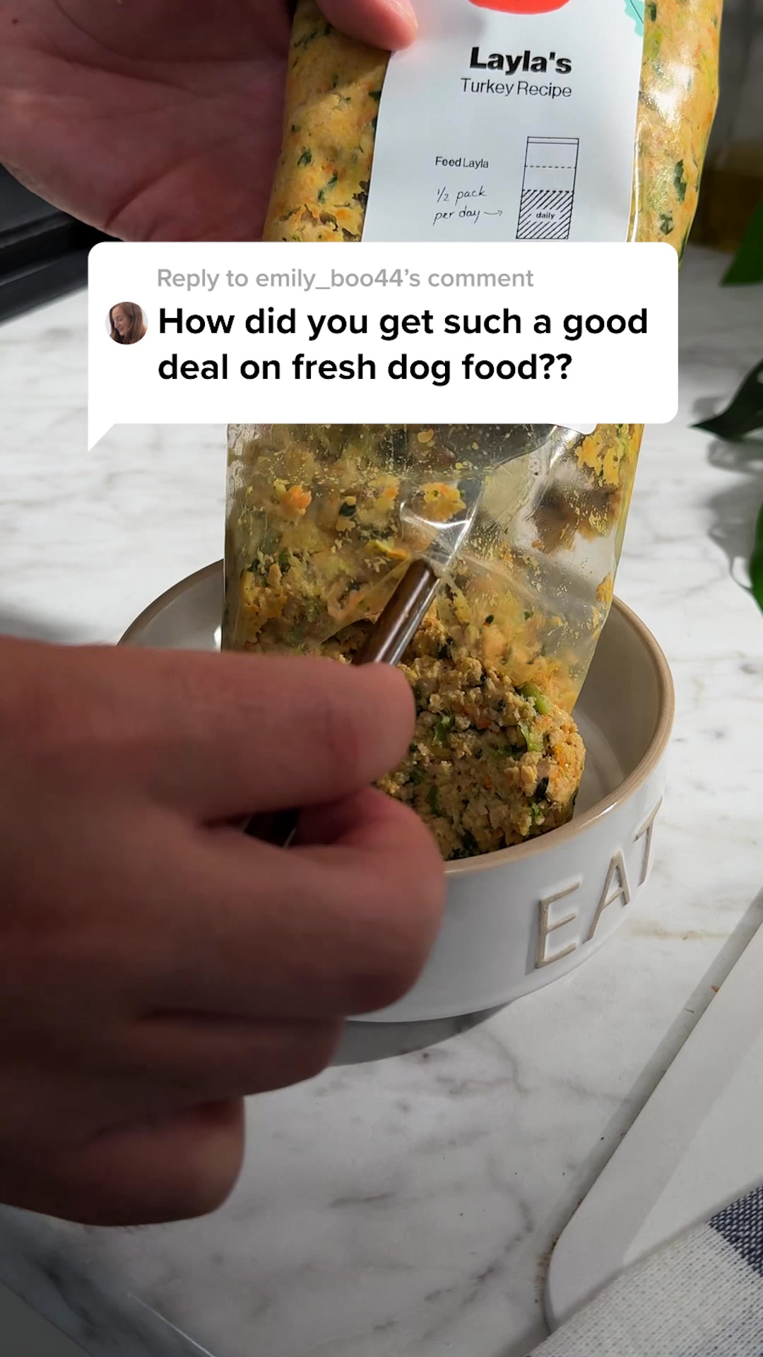 A person is holding a bag of fresh dog food and pouring it into a white bowl. A comment bubble is overlaid on the image, displaying a question from a user about getting a good deal on fresh dog food. The dog food appears to be a mix of ground meat and vegetables. The packaging for the dog food is visible at the top of the image, showing the brand name 'Layla's Turkey Recipe'.