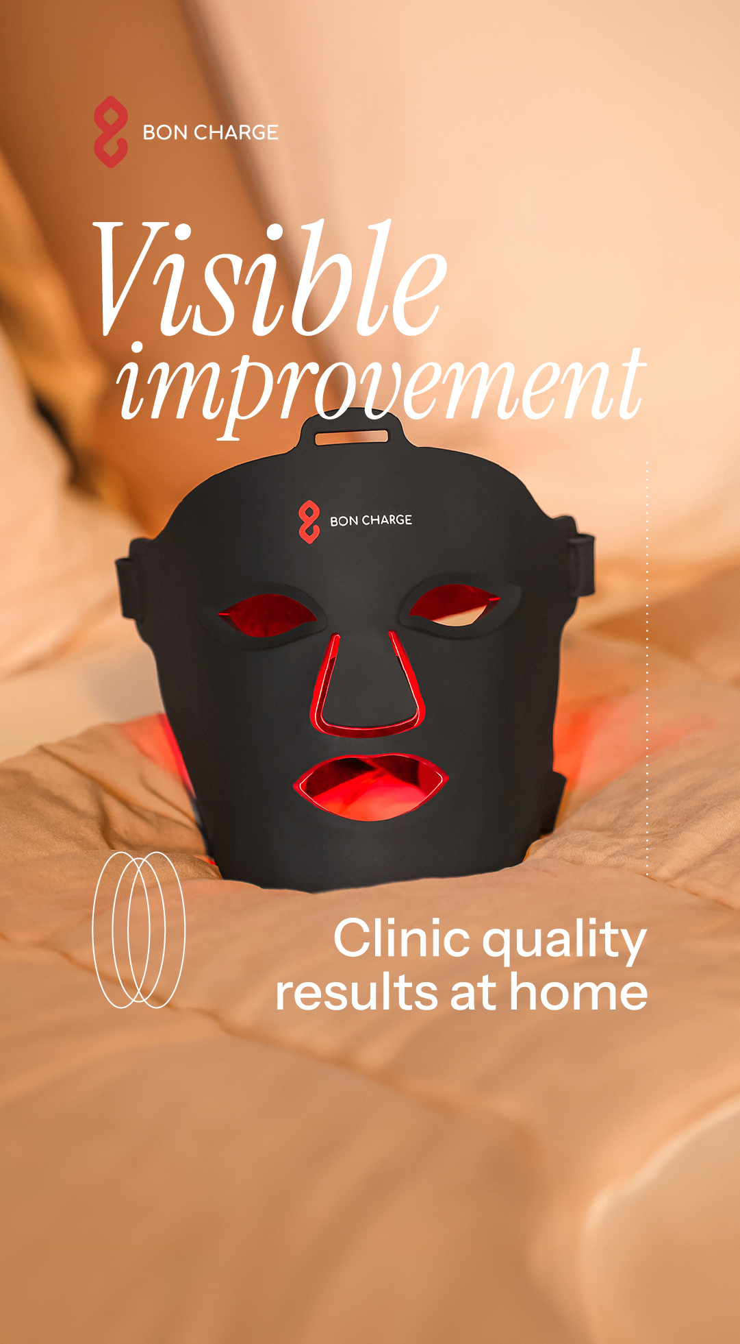A black LED face mask with red lights glowing from the eye, nose, and mouth openings is shown in close-up, resting on a textured, peachy-orange surface. White text overlays the image, with "Visible improvement" in a large, elegant script at the top, and "Clinic quality results at home" in a smaller, sans-serif font at the bottom. The Bon Charge logo is visible on the mask.