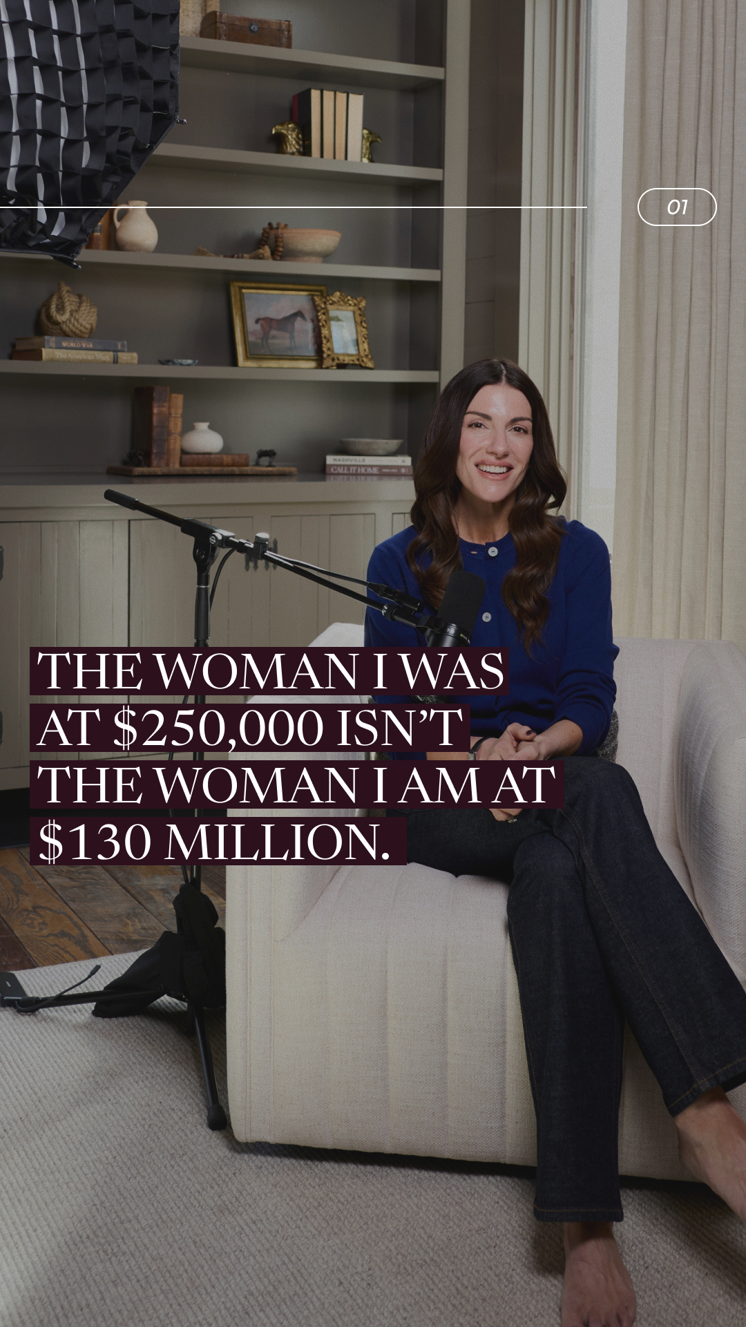 A woman is sitting in a chair in front of a bookshelf. Text is overlaid on the image. The text reads: "THE WOMAN I WAS AT $250,000 ISN'T THE WOMAN I AM AT $130 MILLION." The woman is smiling and looking at the camera. The scene appears to be a home office or living room.