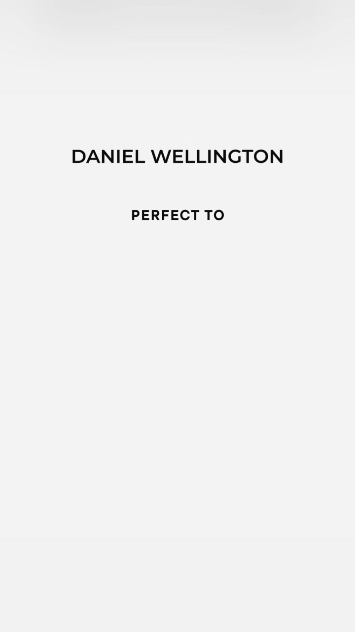 The creative is a minimalist, text-only ad with a plain, light grey background. The brand name "DANIEL WELLINGTON" is displayed prominently in large, black, sans-serif capital letters across the top half of the screen. Below this, centered and in slightly smaller, bold black capital letters, is the phrase "PERFECT TO". The overall impression is clean, modern, and focused on the brand and a simple statement.