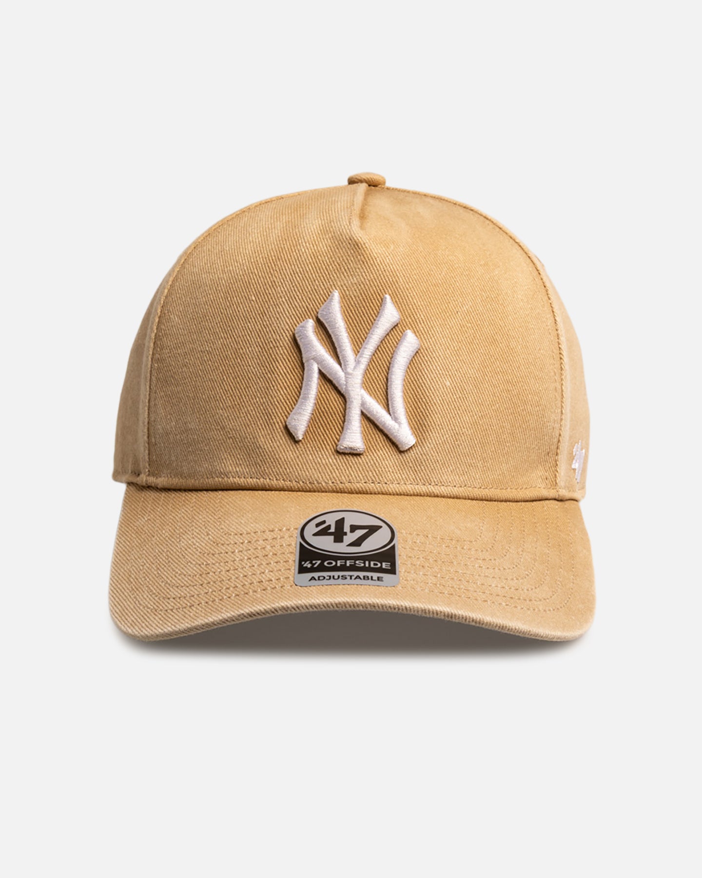 A tan-colored baseball cap with a white embroidered New York Yankees logo is shown centered against a light gray background. A small black and white tag with "47 OFFISIDE ADJUSTABLE" is visible on the brim. The text "Your rotation needs a fresh lid 👀" is overlaid at the top of the image.
