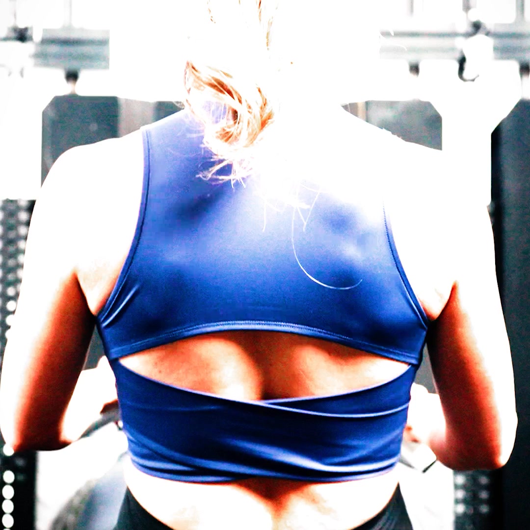 The image shows the back of a woman wearing a blue sports bra in a gym setting. She has her hair tied up in a bun. The text overlay reads "From the squat rack to the streets, REP apparel keeps you looking sharp and feeling unstoppable." The ad is for REP Fitness apparel, suggesting versatility for both workouts and everyday wear.