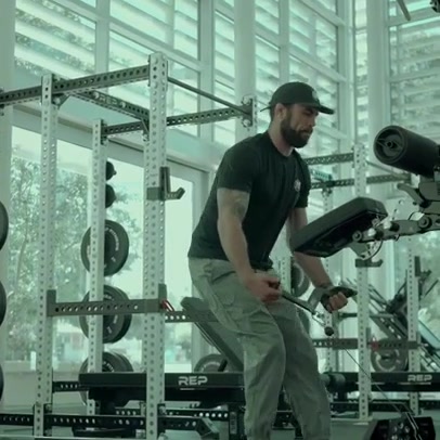 A man in athletic wear is performing a seated row exercise using a weight machine in a gym. The gym appears to be well-equipped with various weight racks and machines. Text overlaid on the image reads "Trusted by 500K+ customers worldwide. Build your home gym & crush your goals. Shop now".