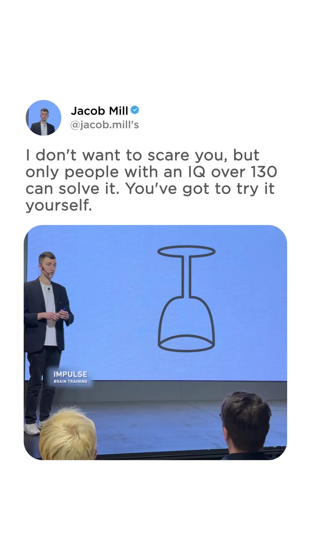A man in a suit stands on a stage in front of a large screen displaying a simple line drawing of a wine glass. The text overlay reads, "I don't want to scare you, but only people with an IQ over 130 can solve it. You've got to try it yourself." The man is identified as Jacob Mill, and the screen also shows the text "IMPULSE BRAIN TRAINING." The overall impression is a challenge or a puzzle presented to the audience.