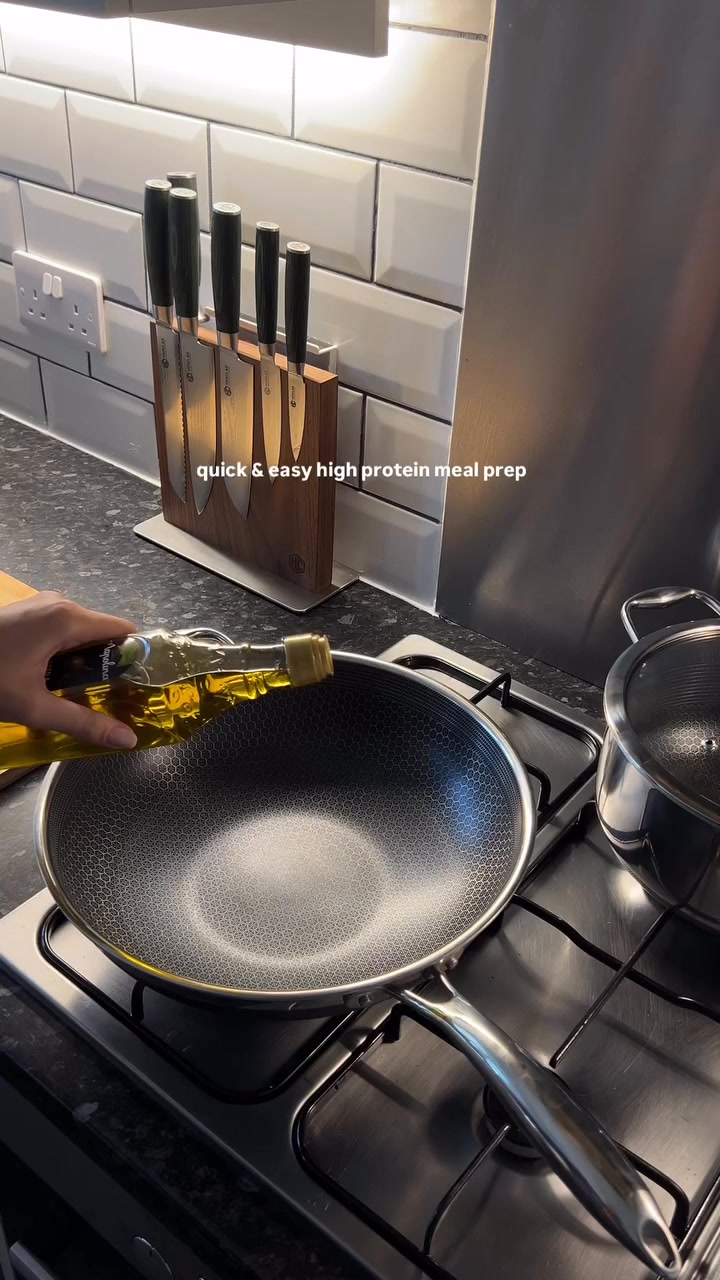 A close-up shot shows a hand pouring cooking oil into a HexClad wok on a stovetop. The background features a clean kitchen with white subway tiles and a magnetic knife block. Overlay text reads "quick & easy high protein meal prep." The ad copy highlights a customer testimonial and lists the product's key features and benefits, emphasizing its durability and versatility.