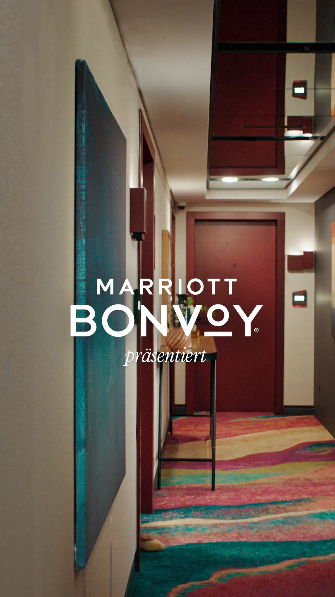 The image shows a hotel hallway with a colorful, abstract carpet. The Marriott Bonvoy logo and the German text "präsentiert" (presents) are overlaid on the image. The text "Machen Sie mehr aus Ihrer nächsten Geschäftsreise, entdecken Sie unsere Hotelmarken. Reisen, die immer in Erinnerung bleiben." is also overlaid, suggesting a connection between business travel and memorable experiences through Marriott's hotel brands.