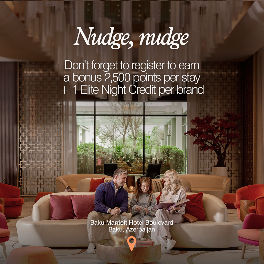 A family of three, a man, a woman, and a young girl, are seated on a curved sofa in a luxurious hotel lobby. The text "Nudge, nudge" is displayed prominently at the top of the image in a stylized font. Below it, smaller text reads: "Don't forget to register to earn a bonus 2,500 points per stay + 1 Elite Night Credit per brand." The location "Baku Marriott Hotel Boulevard, Baku, Azerbaijan" is also visible on the screen.