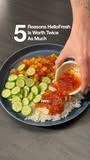 A close-up shot of a plate of food with rice, sliced cucumbers, and a saucy topping being poured over it. White text overlaid on the image reads "5 Reasons HelloFresh Is Worth Twice As Much." The text suggests a listicle format, highlighting the value proposition of the meal kit service. The overall visual focuses on the appetizing presentation of a home-cooked meal.