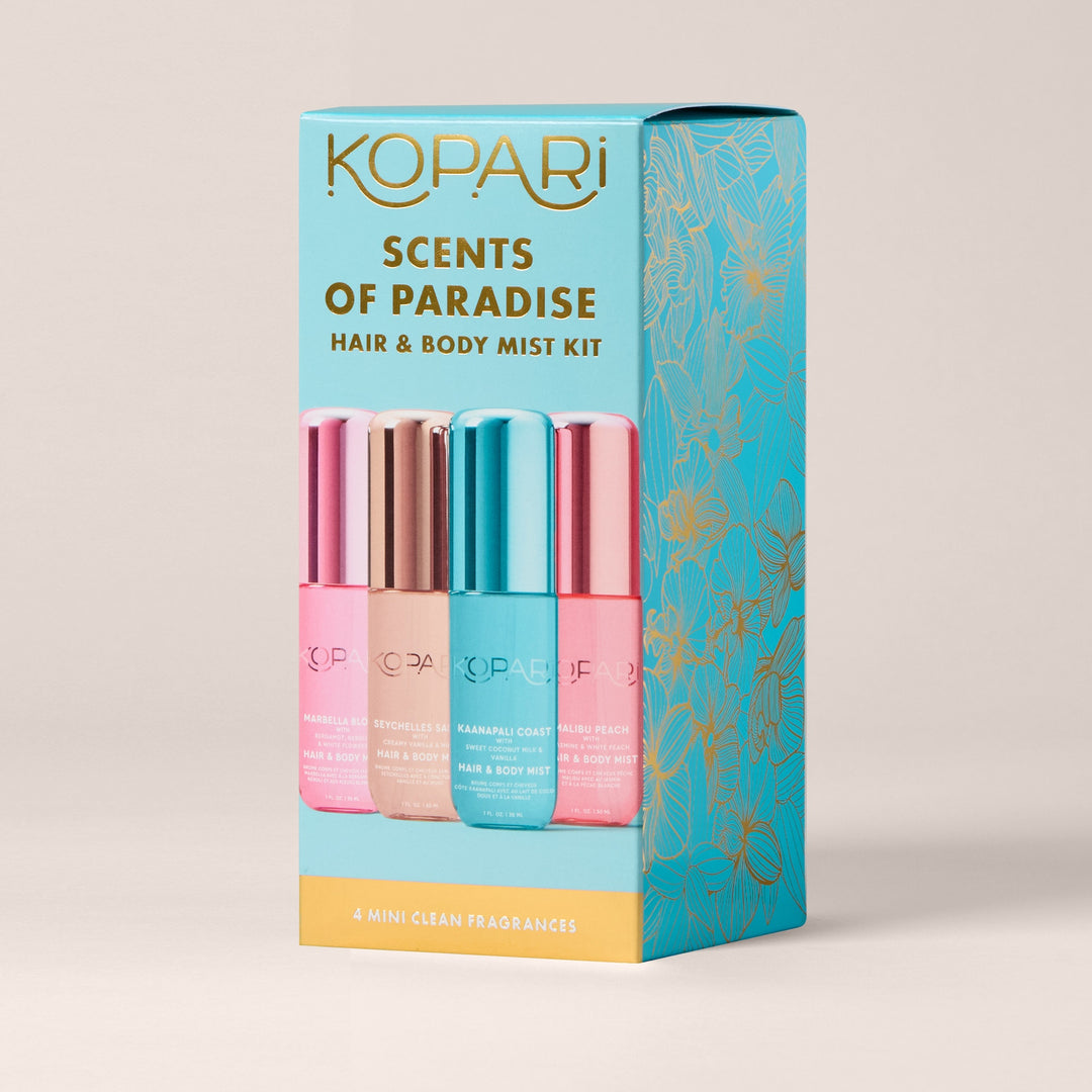 A product shot of the Kopari Scents of Paradise Hair & Body Mist Kit. The kit contains four mini mist bottles in pink, rose gold, teal, and pink, arranged in a box with a teal and gold floral design. The text "KOPARI SCENTS OF PARADISE HAIR & BODY MIST KIT" is prominently displayed at the top of the box. Below the bottles, the text "4 MINI CLEAN FRAGRANCES" is visible on a yellow band. The overall image is clean and highlights the product packaging and contents.