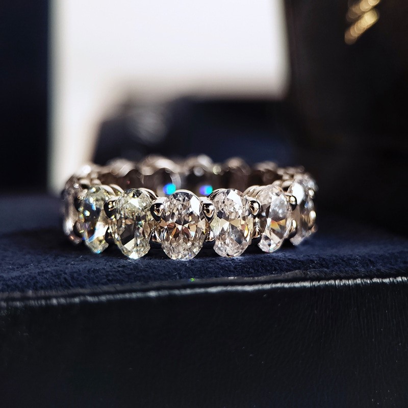 A close-up, high-quality product shot of an eternity band ring with multiple oval-cut diamonds. The ring is set against a dark, textured surface, possibly velvet. The diamonds are brilliant and reflect light, with subtle rainbow glints visible. Text overlays the image, announcing an "Unbelievable Deal Alert!" and promoting "3 amazing products for just €0.99!" The overall impression is luxurious and emphasizes a significant discount.