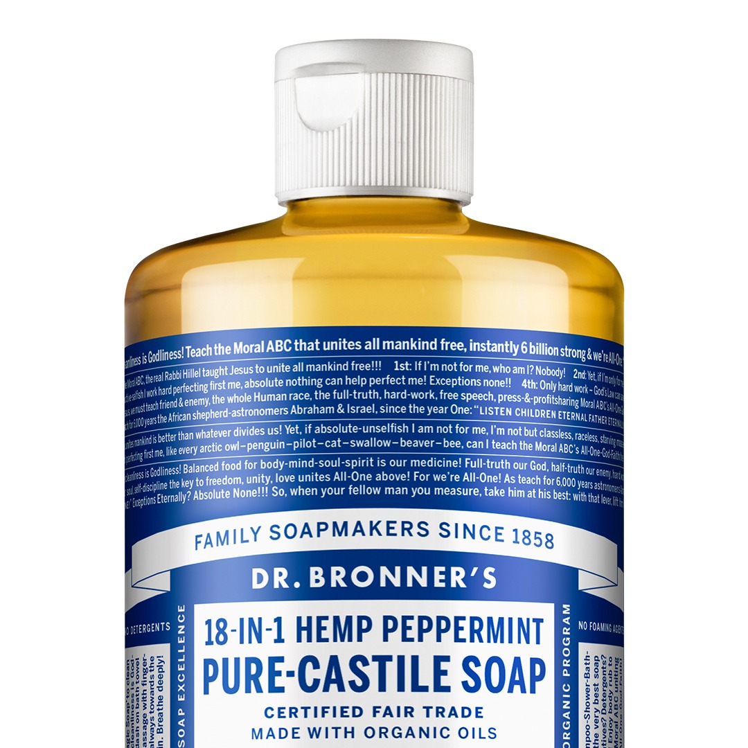 A close-up shot of a bottle of Dr. Bronner's 18-in-1 Hemp Peppermint Pure-Castile Soap. The label is predominantly blue and white with a lot of text. The top of the label has the text "FAMILY SOAPMAKERS SINCE 1858" and "DR. BRONNER'S". Below that, it reads "18-IN-1 HEMP PEPPERMINT PURE-CASTILE SOAP" in large font. The text "CERTIFIED FAIR TRADE MADE WITH ORGANIC OILS" is at the bottom of the label. The hook "“The soap with all the writing on it” is a family-owned, activist company!" is overlaid on the image. The rest of the label contains extensive text detailing the product's ingredients and philosophy.