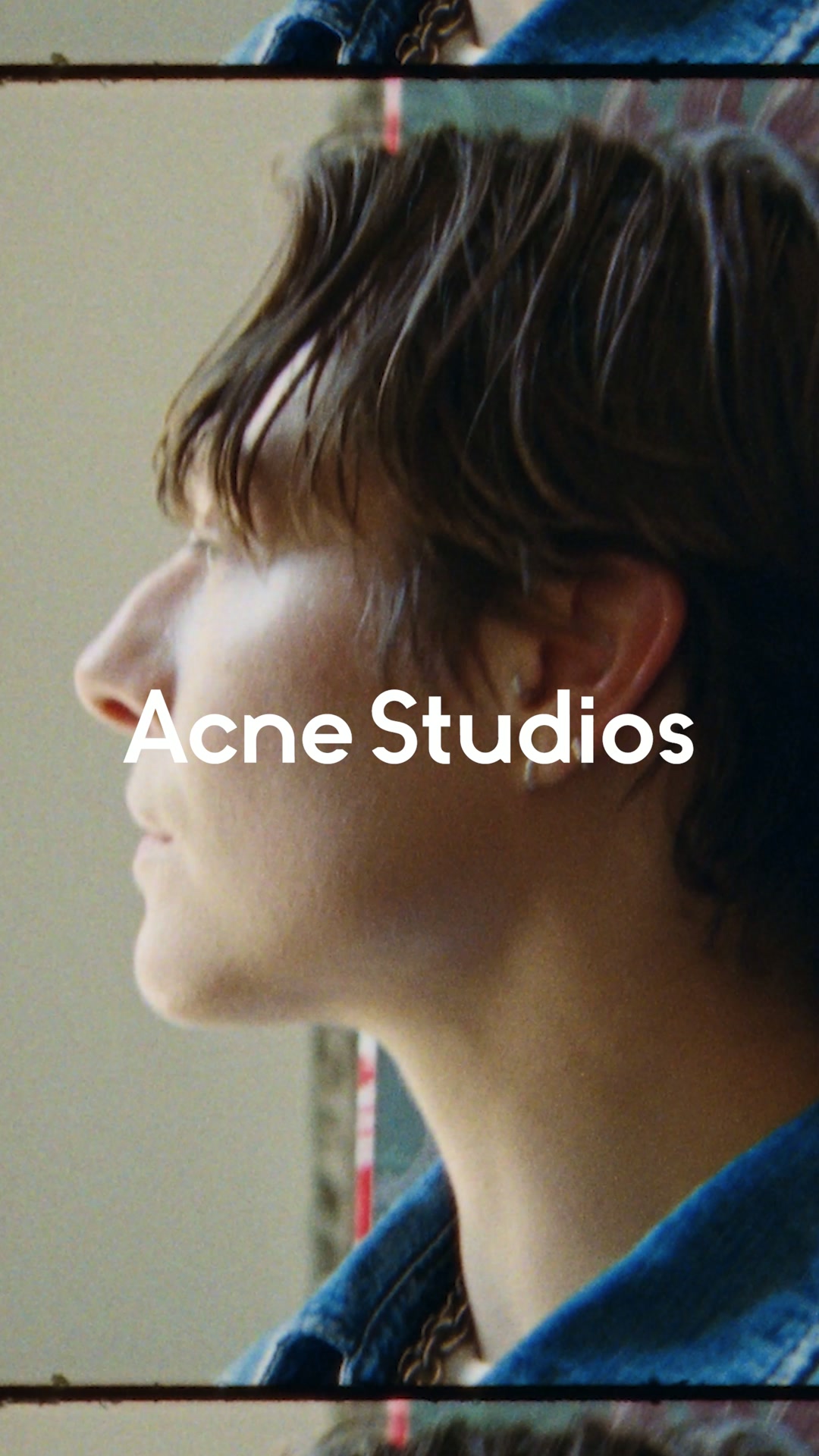 A close-up profile shot of a person's face and hair, with the text "Acne Studios" overlaid in white. The person is looking off to the left, with soft lighting. The background is a muted, textured wall. The text "Thirty Years of Acne Studios" is presented as the hook, followed by a description of the actor embodying the brand's spirit and a call to discover denim.