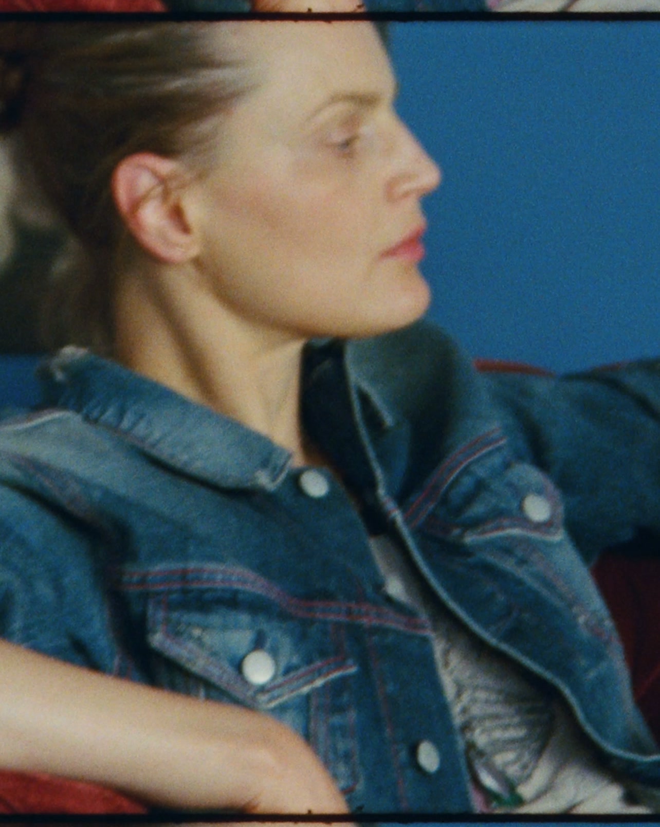 A close-up profile shot of a woman with blonde hair pulled back, wearing a denim jacket over a patterned shirt. She is looking to the right with a neutral expression against a blue background. The text "Thirty years of Acne Studios" is overlaid on the image. The accompanying copy explains that Acne Studios has collaborated with Nan Goldin to create portraits celebrating the brand's 30th anniversary with friends who have shaped its story.