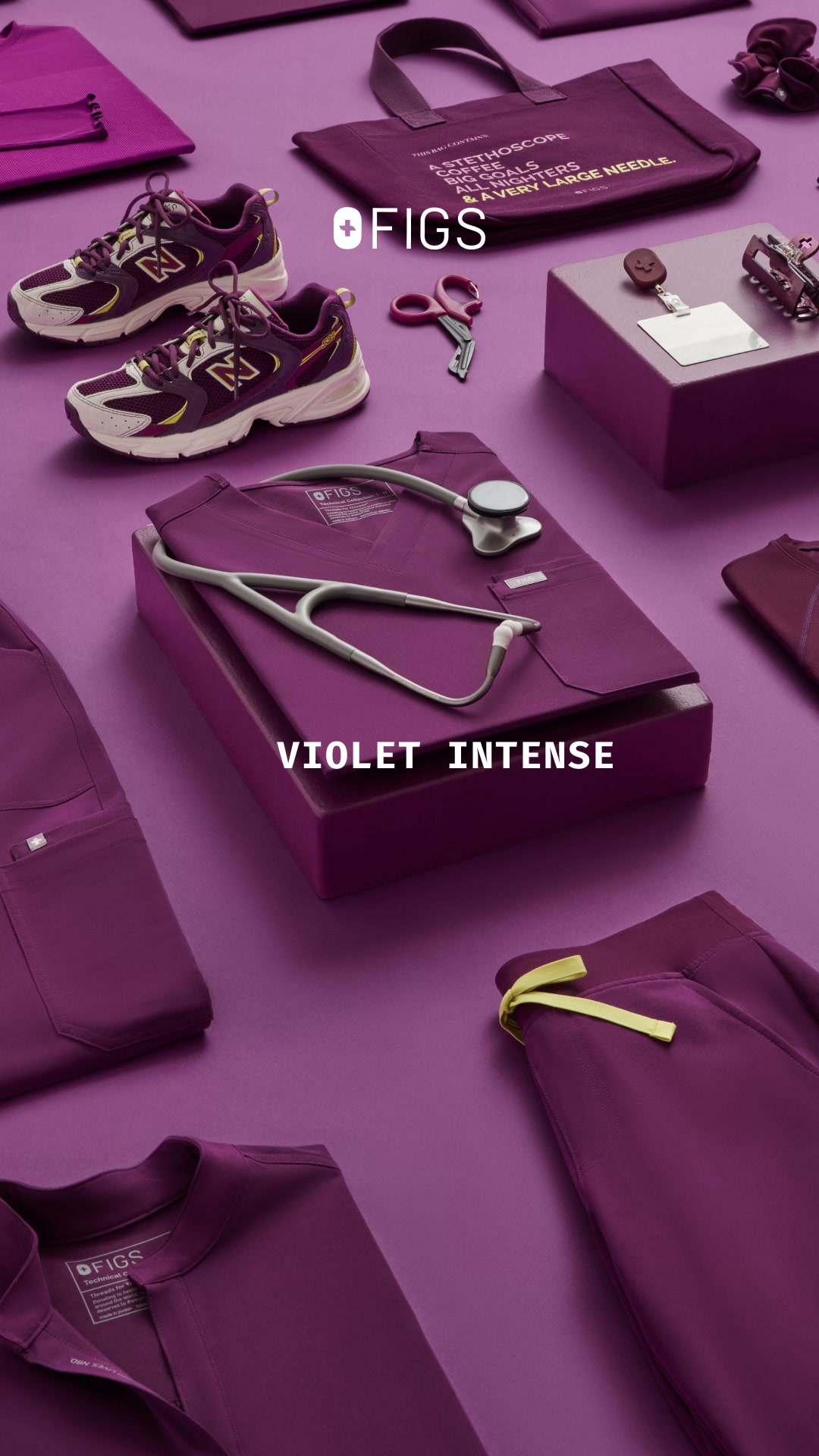A flat lay arrangement of Figs brand medical apparel and accessories in various shades of purple. The items include shoes, a tote bag with text, scissors, a stethoscope, and scrubs. The text "VIOLET INTENSE" is overlaid in large white sans-serif font across the center of the image, highlighting the color of the apparel. The overall presentation is clean and organized, showcasing the product line in a visually appealing manner.