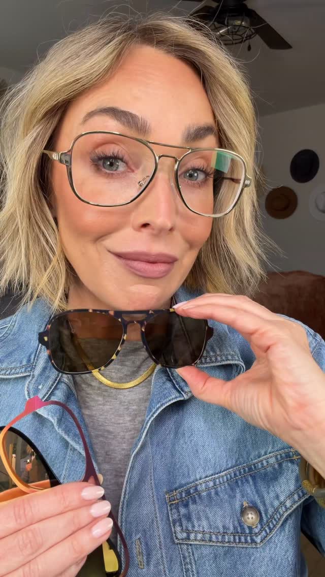 A woman with blonde hair, wearing glasses and a denim jacket, holds up two pairs of sunglasses. She is looking at the camera and smiling. Text overlays appear on the screen, asking "Ok, but why is this the best find ever?!" and "Listen up, if you wear glasses you know how EXPENSIVE it is for multiple frames PLUS prescription sunnies! Well not anymore because Pair Eyewear cracked the code on cute frames AND multiple looks! I’m wearing The Vic and am obsessed with how easy it is to switch things up. Go grab your first pair at @paireyewear and save 15% with my code: JamieCone15 And tell me which look is your favorite? • Classic gold • Ombré • Mirrored sunnies • Tortoise sunnies So glad I don’t have to choose 😘 #PairPartner".