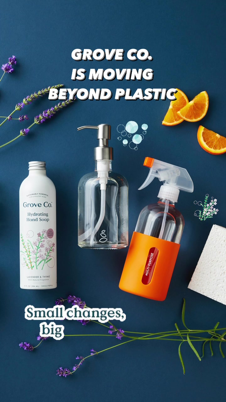 The image displays Grove Co. cleaning products, including a hand soap bottle and a spray bottle, arranged on a dark blue background. Decorative elements like lavender sprigs, orange slices, and bubbles are scattered around the products. White text overlays read "GROVE CO. IS MOVING BEYOND PLASTIC" at the top and "Small changes, big" near the bottom, suggesting a focus on sustainability and environmental impact.