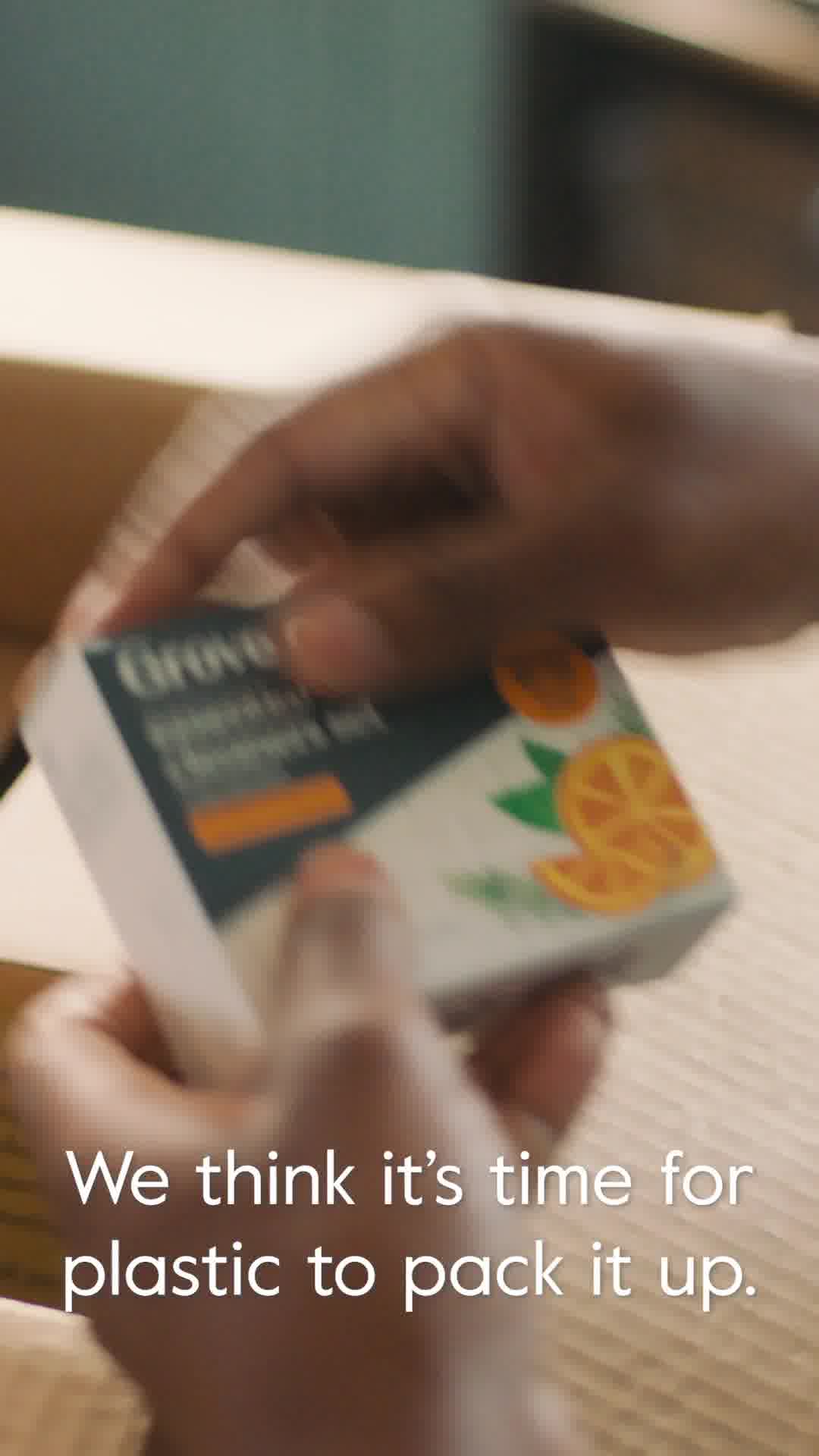 A close-up shot shows hands holding a Grove Collaborative branded product box. The box has an illustration of oranges and green leaves. White text overlays the image, reading "We think it's time for plastic to pack it up." The background is blurred, suggesting an unboxing or product reveal.