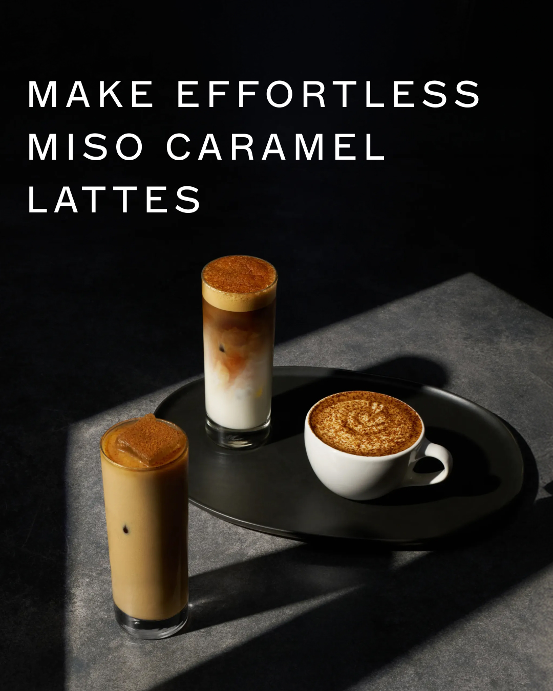 Three glasses of coffee are arranged on a dark surface. The text "MAKE EFFORTLESS MISO CARAMEL LATTES" is overlaid on the top left of the image. The coffee drinks appear to be a latte, an iced latte, and a cappuccino. The lighting is dramatic, with strong shadows cast across the scene.