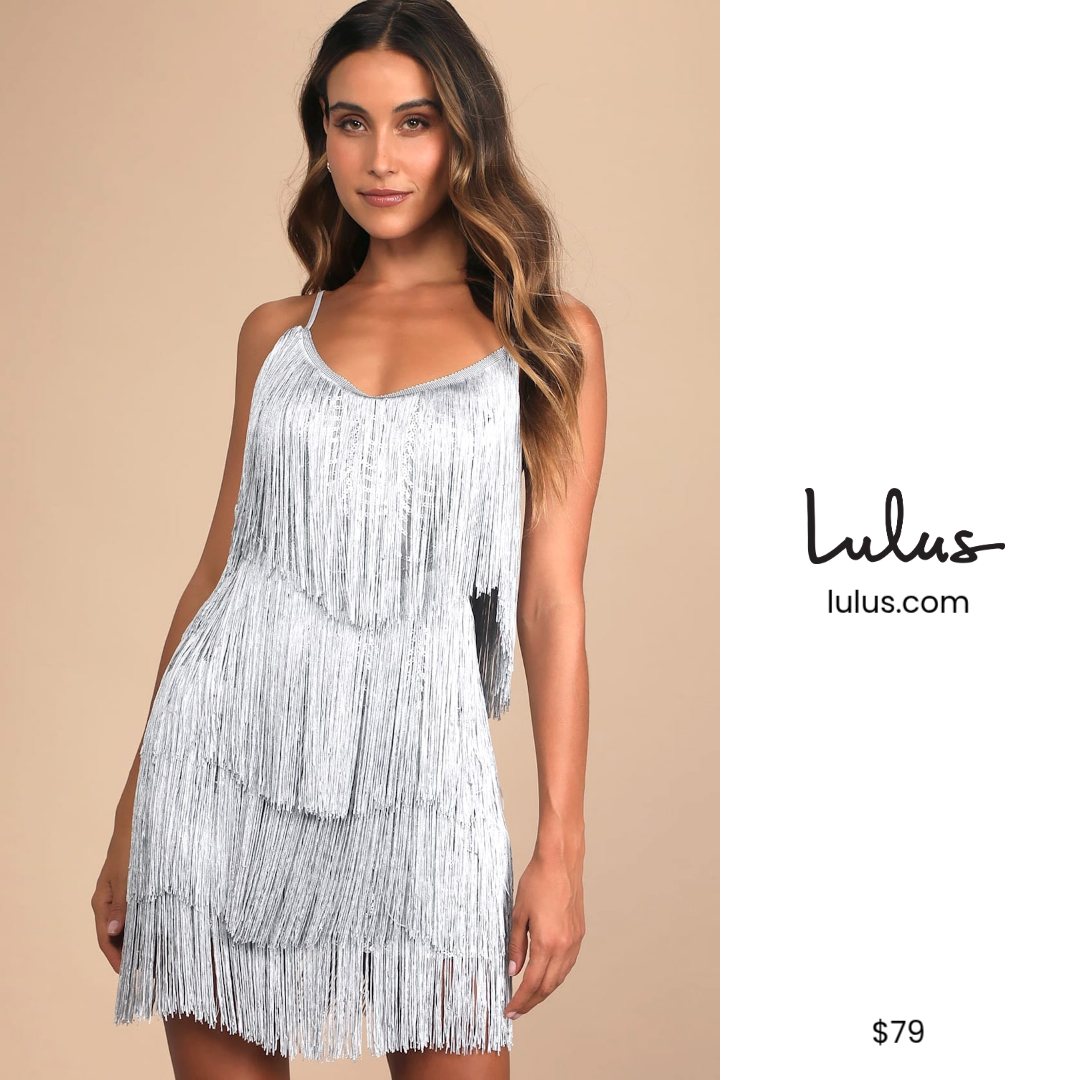 A woman models a short, silver, sequined dress with fringe detailing. The dress has thin spaghetti straps and a V-neckline. The background is a plain beige color. To the right of the woman, the Lulus logo and website are displayed, along with the price '$79'. The text 'Life’s a party. Dress like it.' is overlaid on the image.