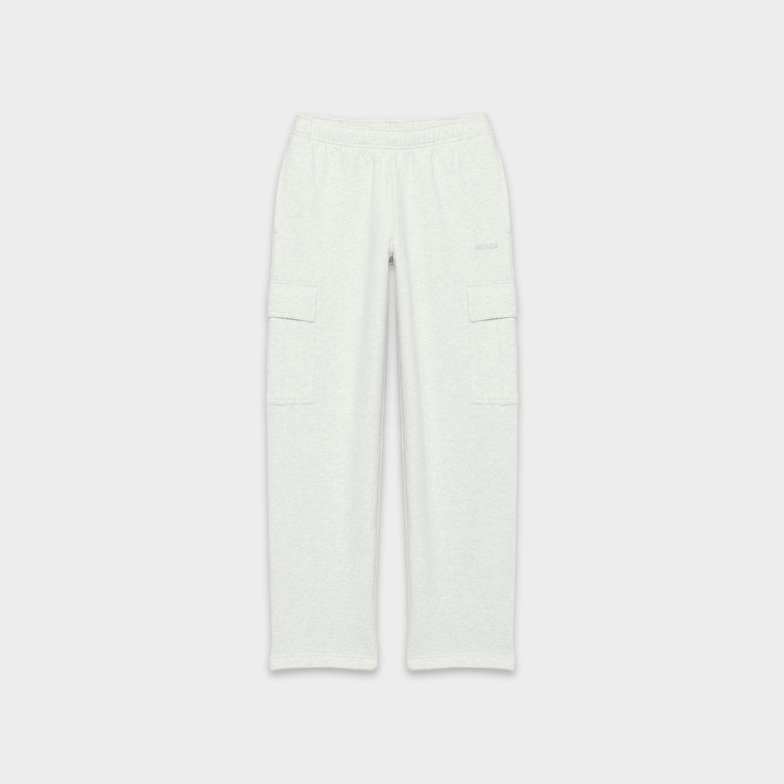 A light grey heathered pair of Aritzia sweatpants is shown against a plain white background. The sweatpants are a relaxed fit with cargo pockets on each thigh. The brand name 'ARITZIA' is subtly embossed in a matching grey tone on the upper right thigh. The text 'Sweatfleece — The world’s best. Wear-everyday styles crafted in endless colours and time-perfected fits.' is overlaid on the image.