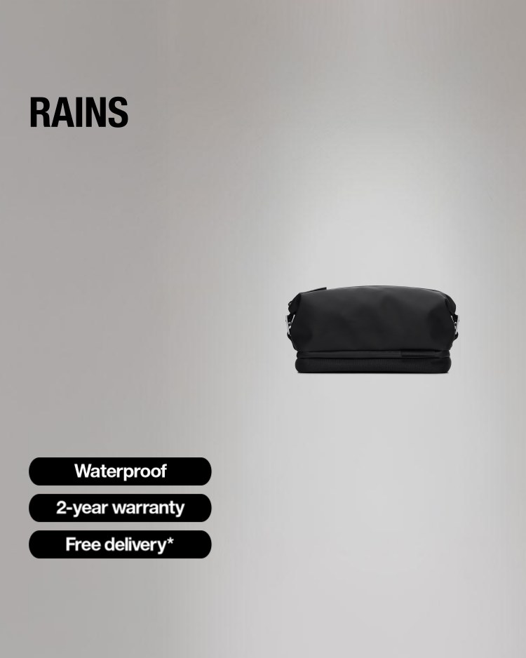 The ad features a black Rains toiletry bag on a grey background. Text overlays highlight key features: "Waterproof", "2-year warranty", and "Free delivery*". The headline states "Get a free Rains gift with purchases over €130 / £130", indicating a promotional offer. The ad also mentions "30-day returns" in the copy, which is not visible on the creative itself.